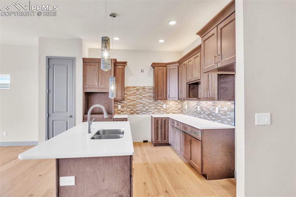 Image 47 of 50: Kitchen with a sink, tasteful backsplash, a kitchen island with sink, and l