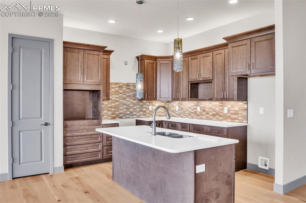 Image 48 of 50: Kitchen featuring pendant lighting, a center island with sink, a sink, ligh