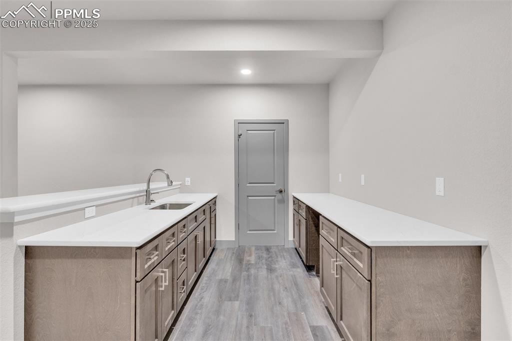 Image 5 of 50: Kitchen with a peninsula, light countertops, light wood finished floors, an