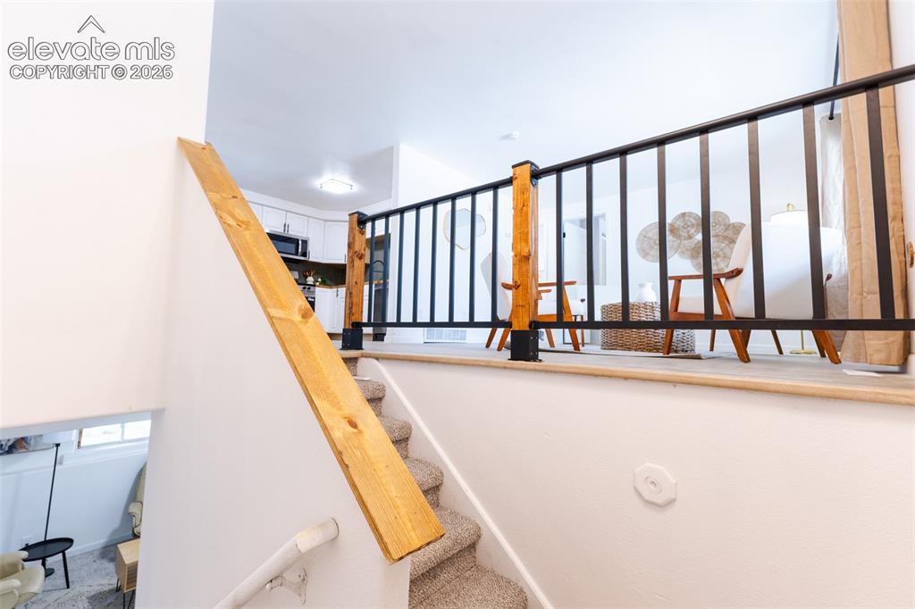 Image 11 of 32: Staircase with carpeted treads and natural wood handrail