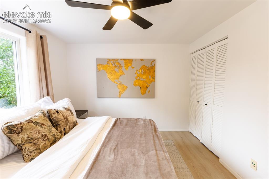 Image 15 of 32: Ceiling fan, wood-finish flooring, white louvered closet doors, and a large