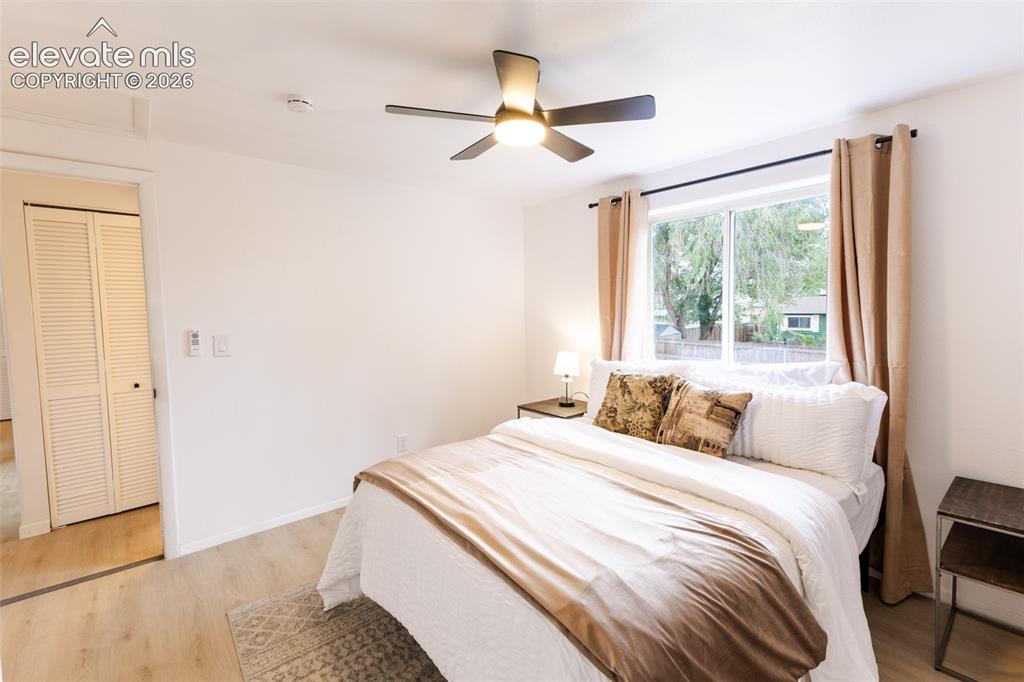 Image 16 of 32: Ceiling fan, wood-finish flooring, white walls, and a window with a dark ro