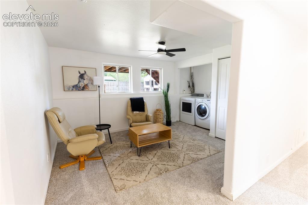Image 19 of 32: Carpeted living area featuring dual windows, a ceiling fan, and an integrat