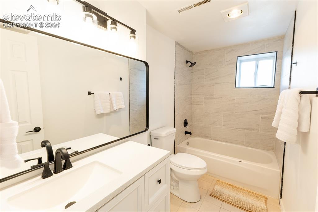 Image 26 of 32: White vanity with an integrated sink, matte black faucet, and an elongated 
