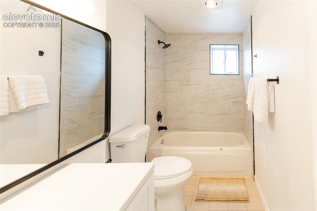 Image 27 of 32: Bathroom featuring a tub/shower combination with tile surround, a window, a