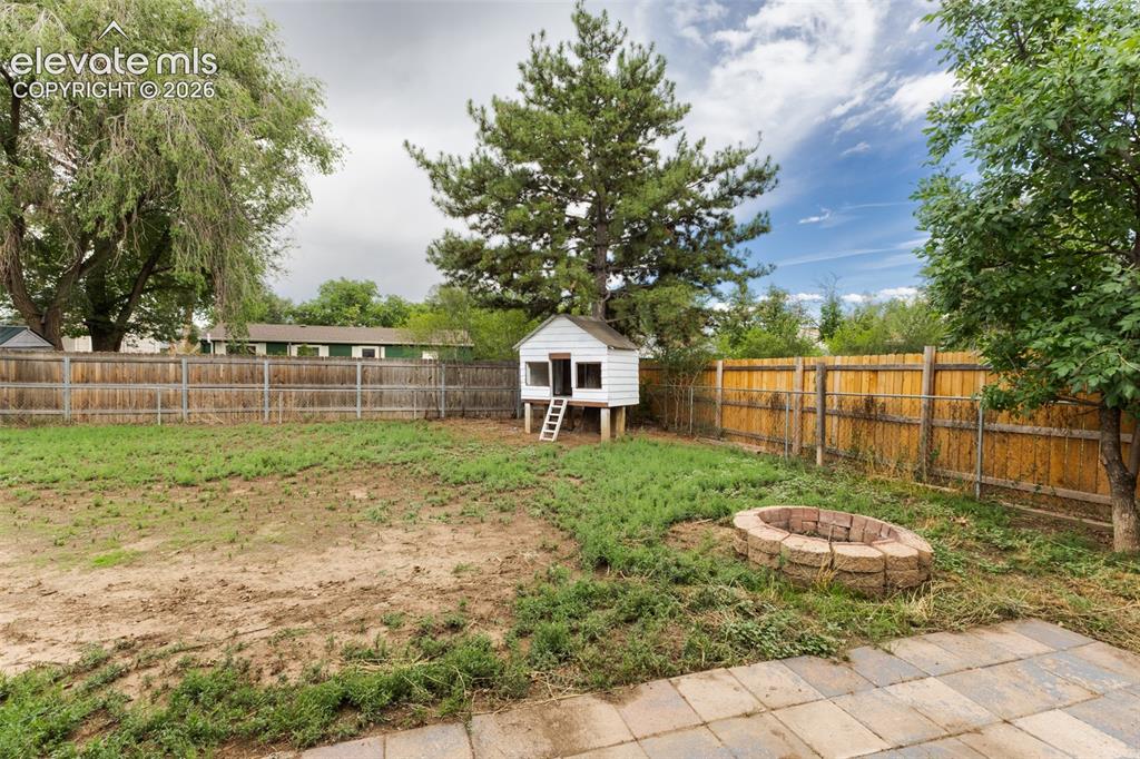 Image 28 of 32: Expansive backyard featuring a paver patio, brick-built fire pit, wood priv