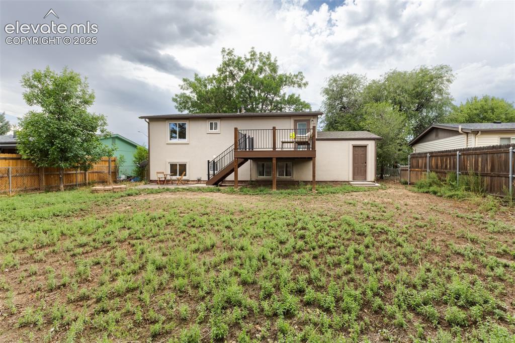 Image 31 of 32: Spacious backyard featuring a wood privacy fence, a raised deck with dark r