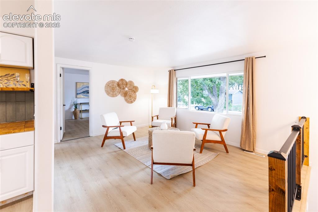 Image 4 of 32: Light wood-finish flooring, white walls, and a large window providing natur