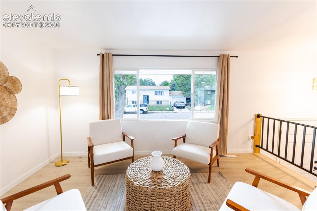 Image 5 of 32: Light-colored wood-finish flooring, white walls, and a large window with bl