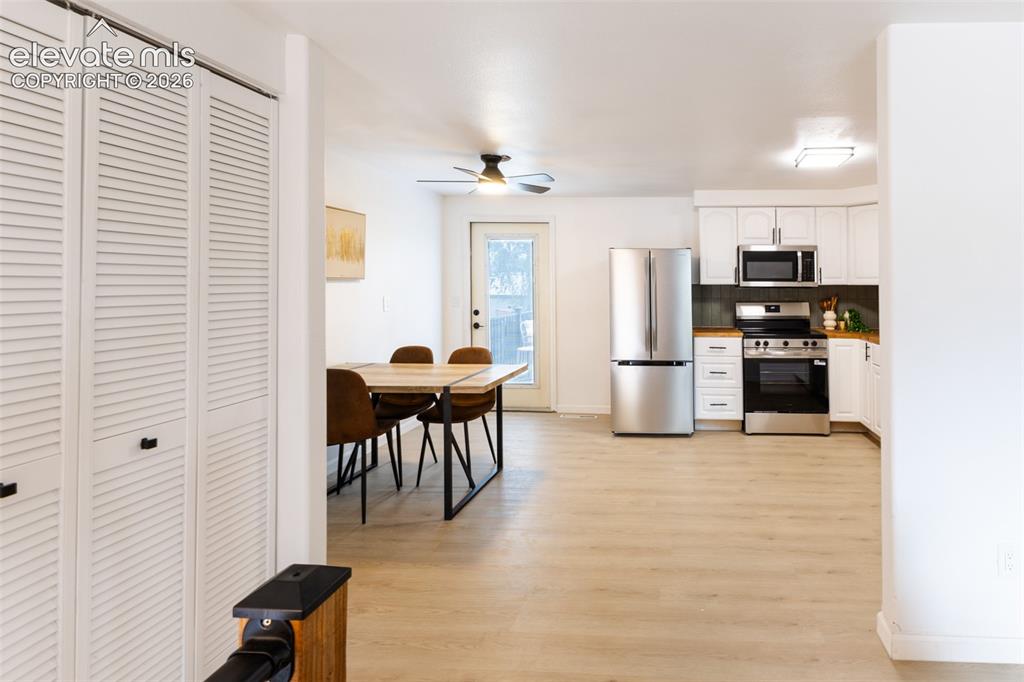 Image 9 of 32: Bright kitchen with white cabinetry, stainless steel appliances, wood-finis