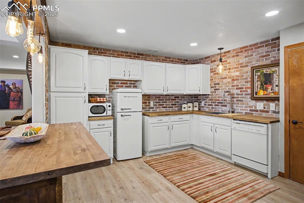 Image 31 of 50: Brick backsplash, SS Kraus sink, and retro (new) fridge add character.  