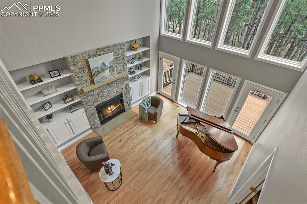 Image 19 of 50: Living area with built in features, a towering ceiling, wood finished floor