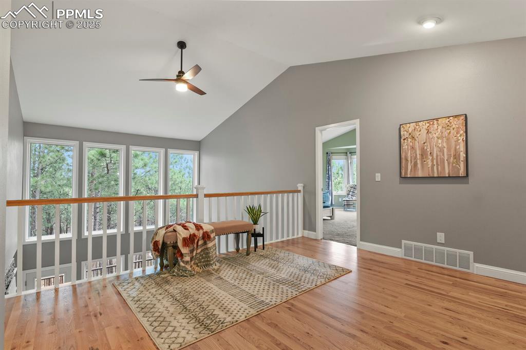 Image 20 of 50: Living area featuring a ceiling fan, lofted ceiling, and wood finished floo