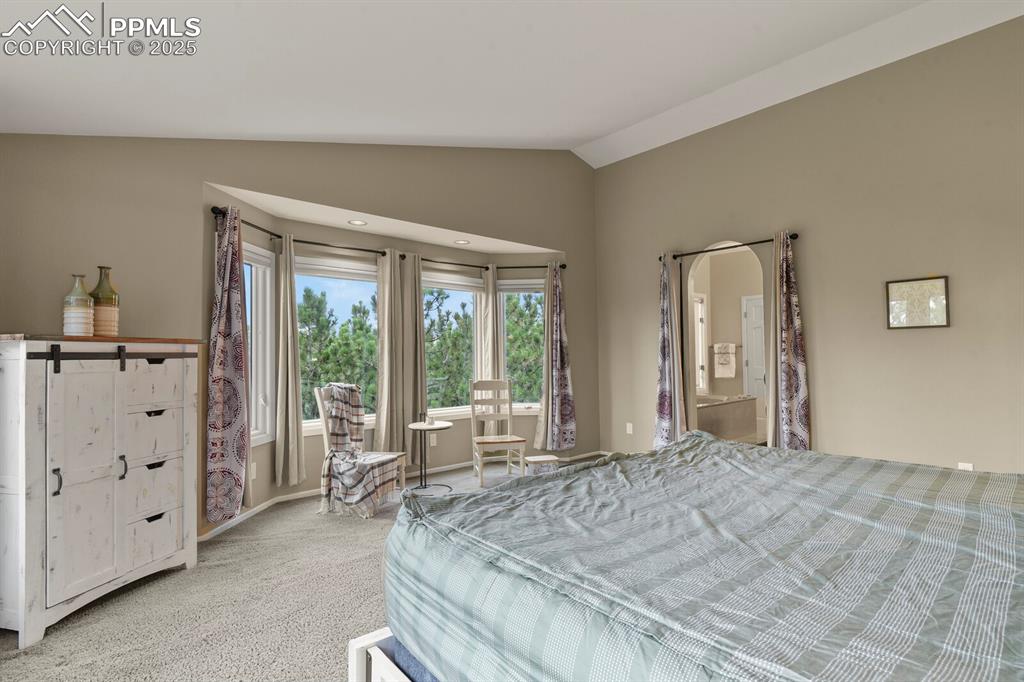 Image 23 of 50: Bedroom featuring vaulted ceiling and light colored carpet
