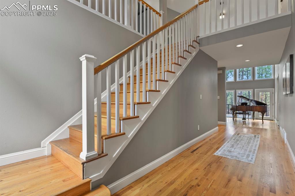 Image 3 of 50: Staircase featuring wood finished floors, a towering ceiling, and recessed
