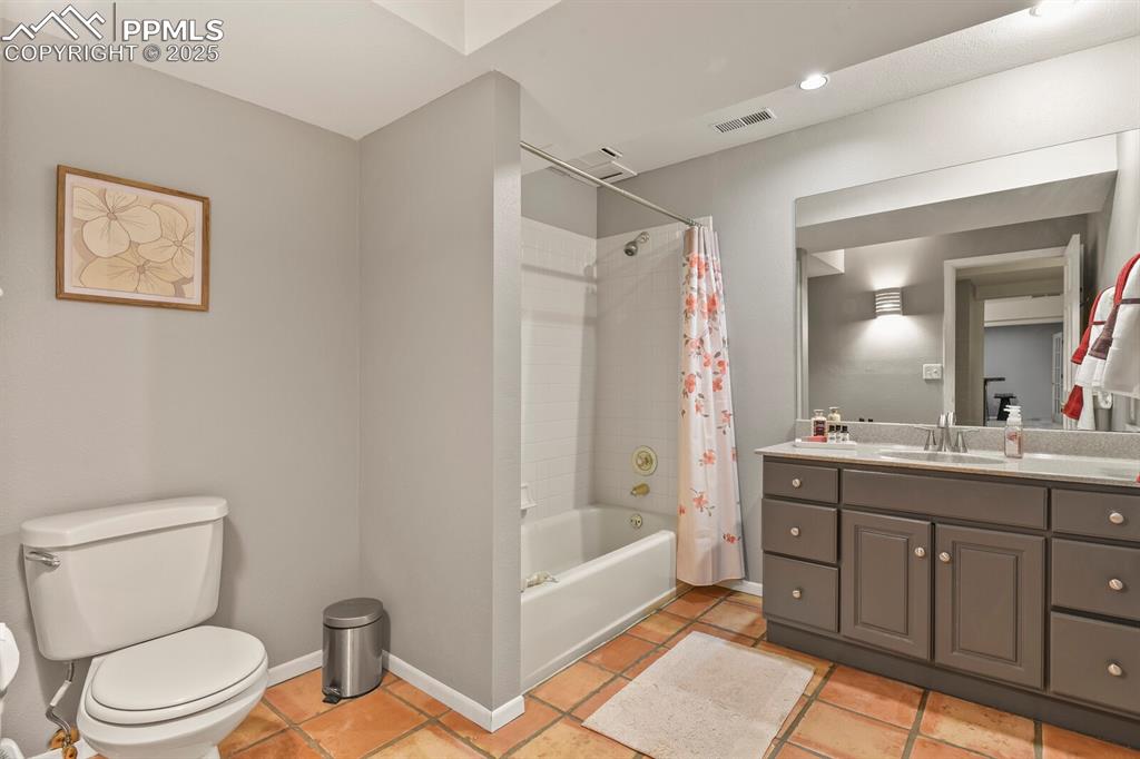Image 40 of 50: Bathroom with vanity, shower / tub combo with curtain, and tile patterned f