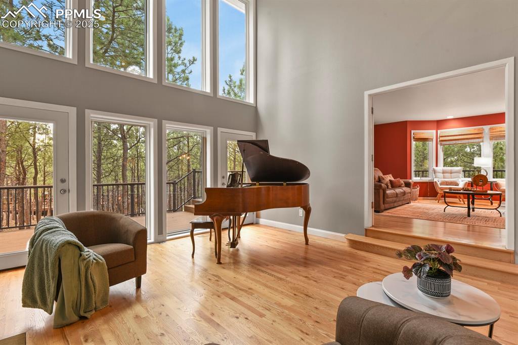 Image 5 of 50: Living area featuring wood finished floors, a towering ceiling, and a desk