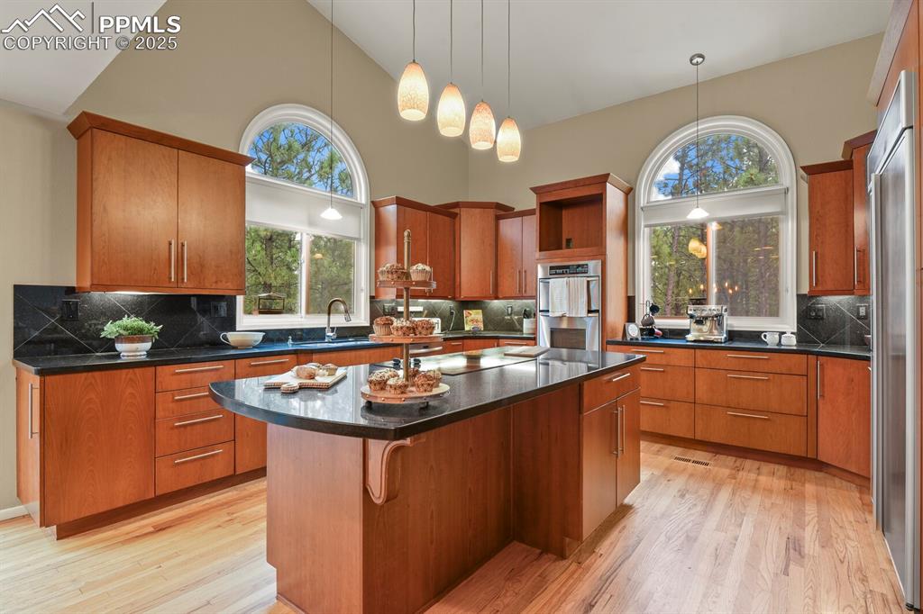 Image 7 of 50: Kitchen featuring tasteful backsplash, a kitchen island, light wood-type fl