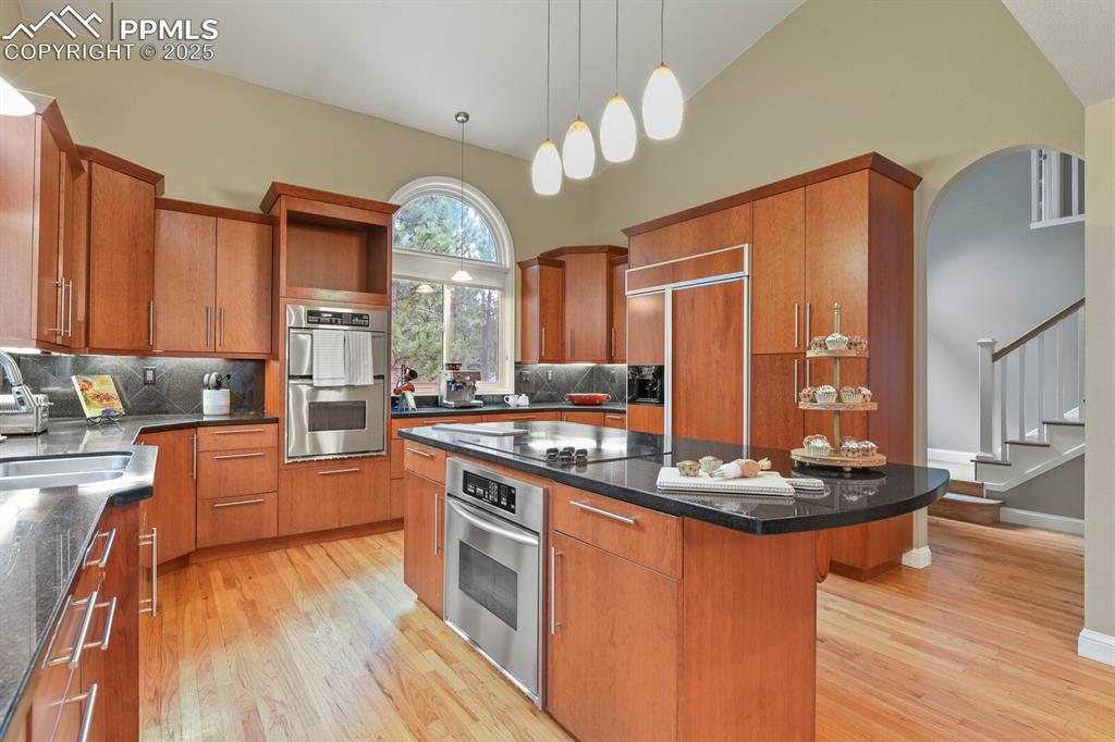 Image 8 of 50: Kitchen featuring lofted ceiling, light wood-style flooring, a center islan
