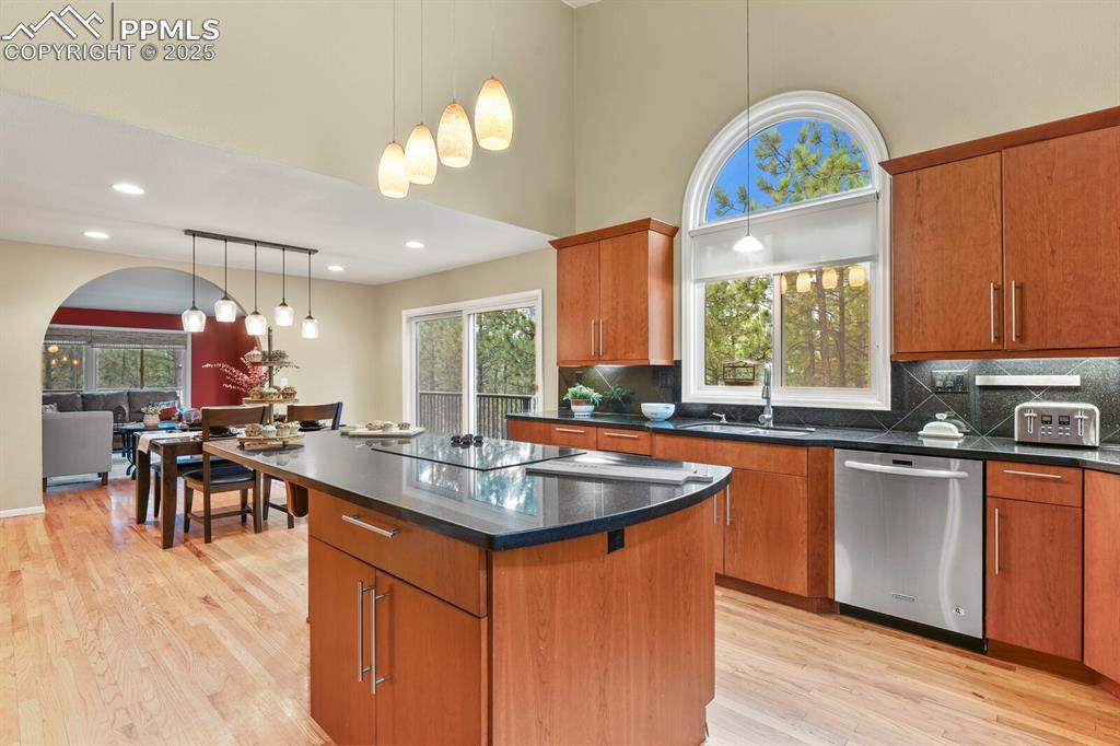 Image 9 of 50: Kitchen with dishwasher, backsplash, dark countertops, a kitchen island, an
