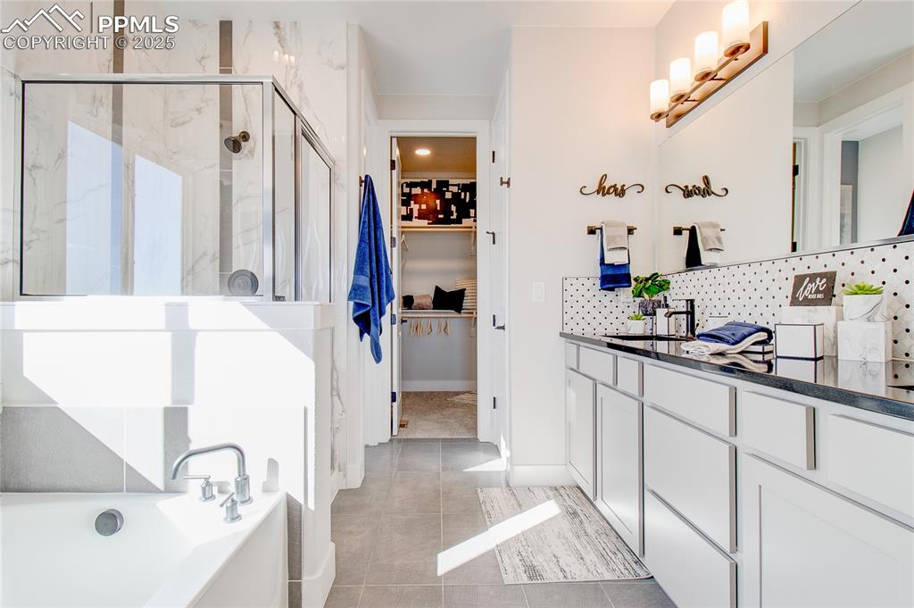 Image 12 of 19: Bathroom featuring a stall shower, a soaking tub, vanity, decorative backsp