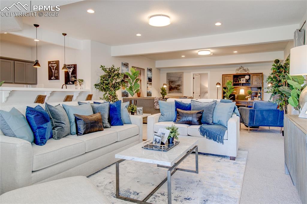 Image 14 of 19: Living area with recessed lighting and light colored carpet