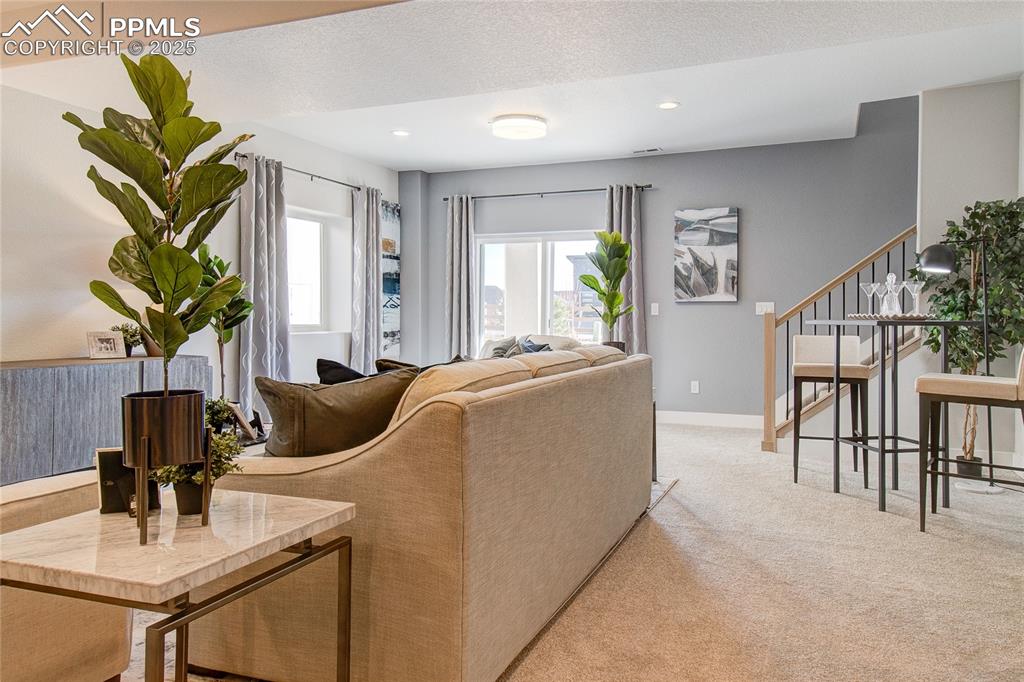 Image 16 of 19: Living area featuring light carpet, stairs, and recessed lighting