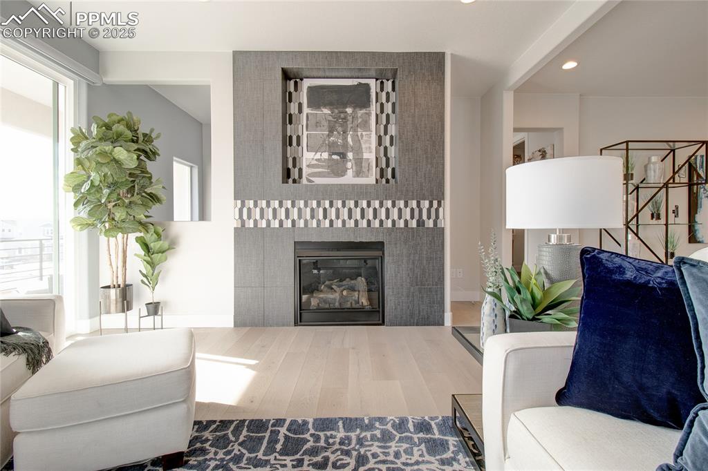 Image 5 of 19: Living area with wood finished floors, a tile fireplace, recessed lighting,