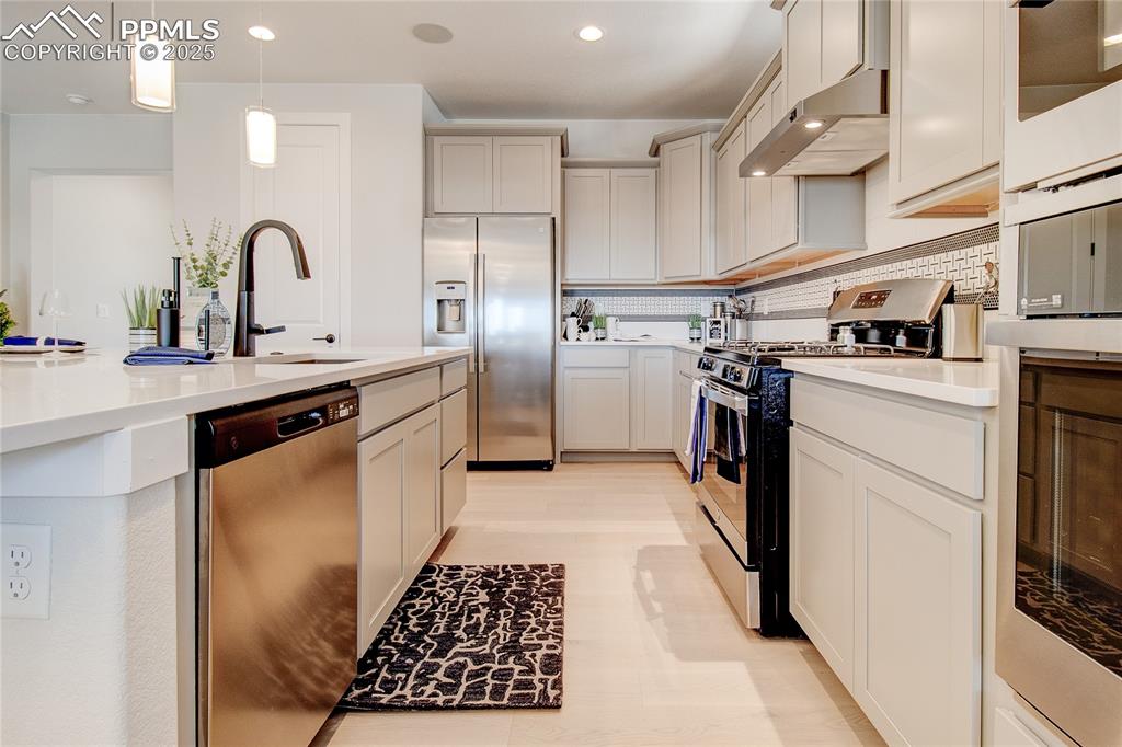 Image 7 of 19: Kitchen with appliances with stainless steel finishes, exhaust hood, recess