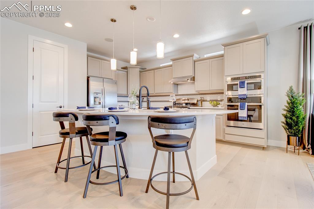 Image 8 of 19: Kitchen with appliances with stainless steel finishes, a breakfast bar, lig