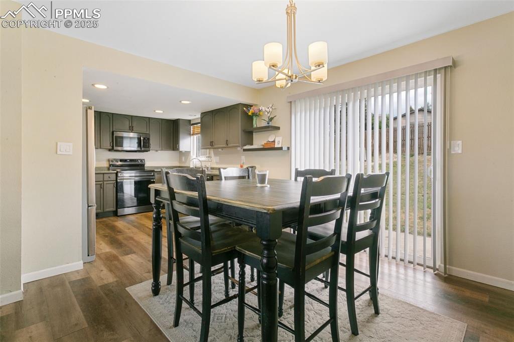 Image 15 of 26: Dining room featuring dark wood-style floors, a chandelier, and recessed li