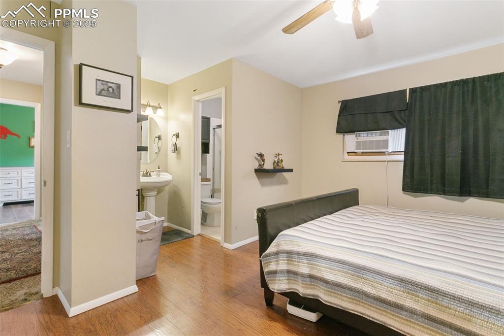 Image 19 of 26: Bedroom featuring wood finished floors, a ceiling fan, and ensuite bathroom
