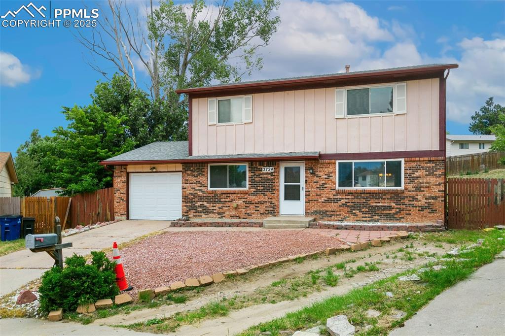 Image 2 of 26: View of front of property featuring an attached garage, brick siding, board