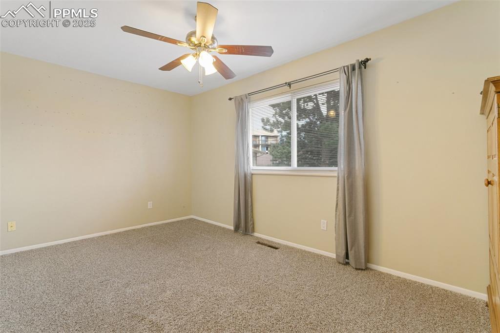 Image 24 of 26: Empty room featuring light carpet and ceiling fan