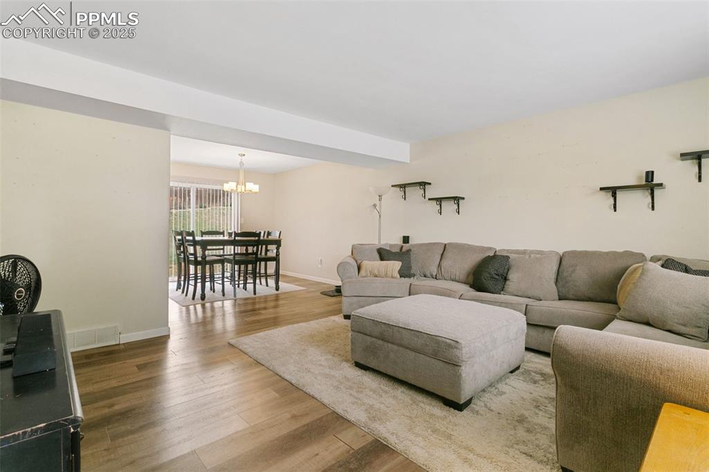 Image 7 of 26: Living room featuring a chandelier and wood finished floors