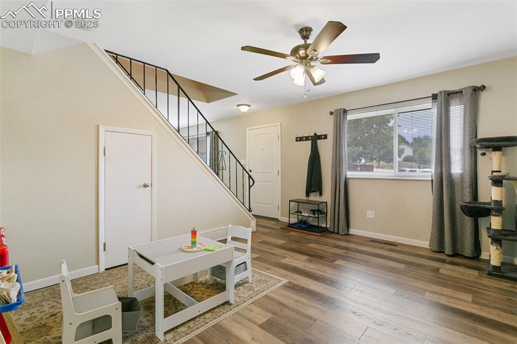 Image 8 of 26: Living room with ceiling fan, stairway, and wood finished floors