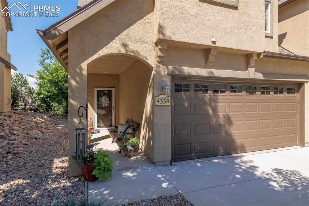 Image 2 of 26: Entrance to property featuring stucco siding, an attached garage, and concr