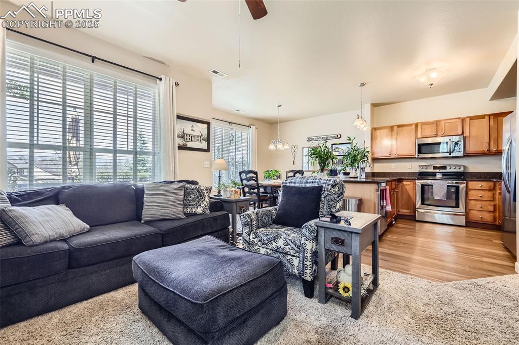 Image 4 of 26: Living area featuring a ceiling fan, light wood-style flooring, and a chand