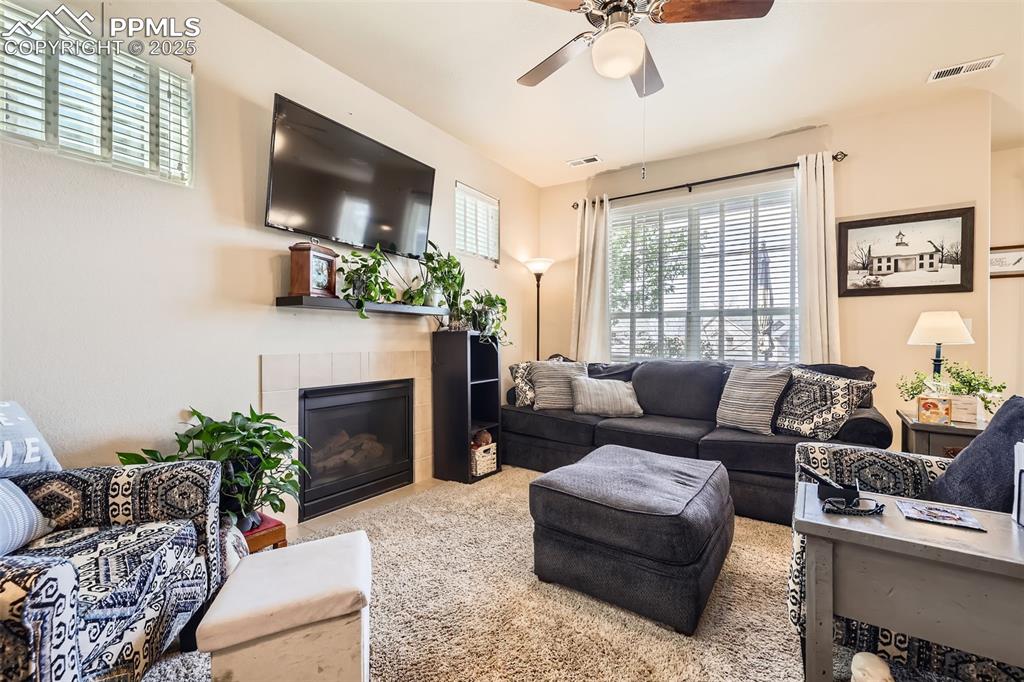 Image 5 of 26: Living area featuring plenty of natural light, a tiled fireplace, carpet fl
