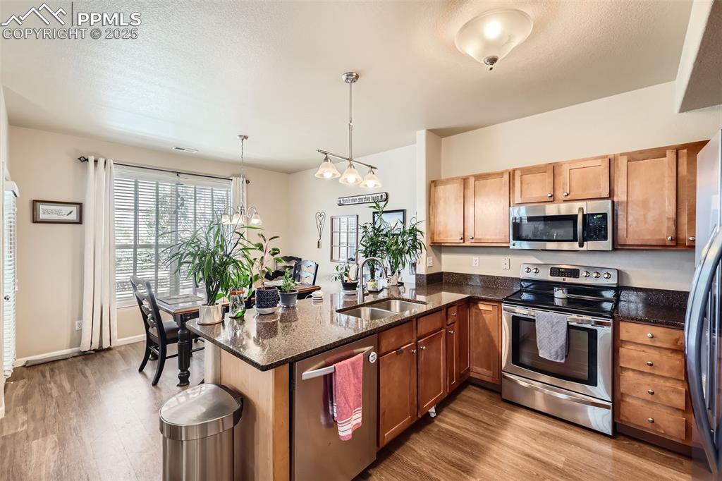 Image 9 of 26: Kitchen with stainless steel appliances, wood finished floors, a peninsula,