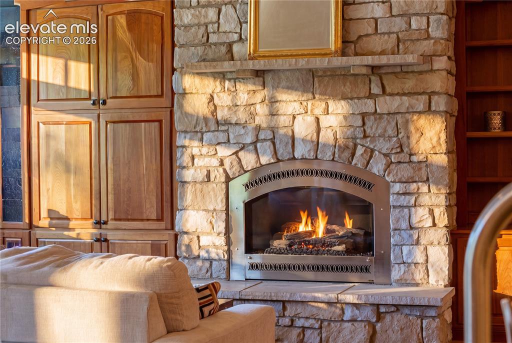 Image 13 of 50: Stone fireplace with an arched firebox and stainless steel surround