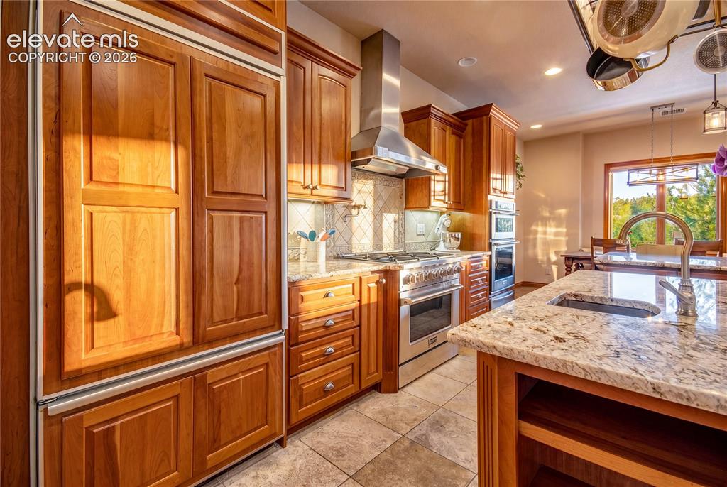 Image 14 of 50: Gourmet kitchen featuring custom wood cabinetry, stainless steel appliances