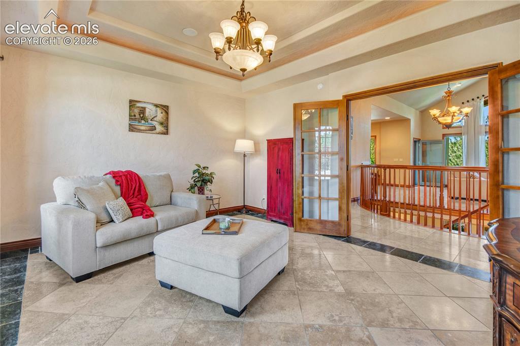 Image 20 of 50: Inviting interior space featuring a tray ceiling with a chandelier, light-t