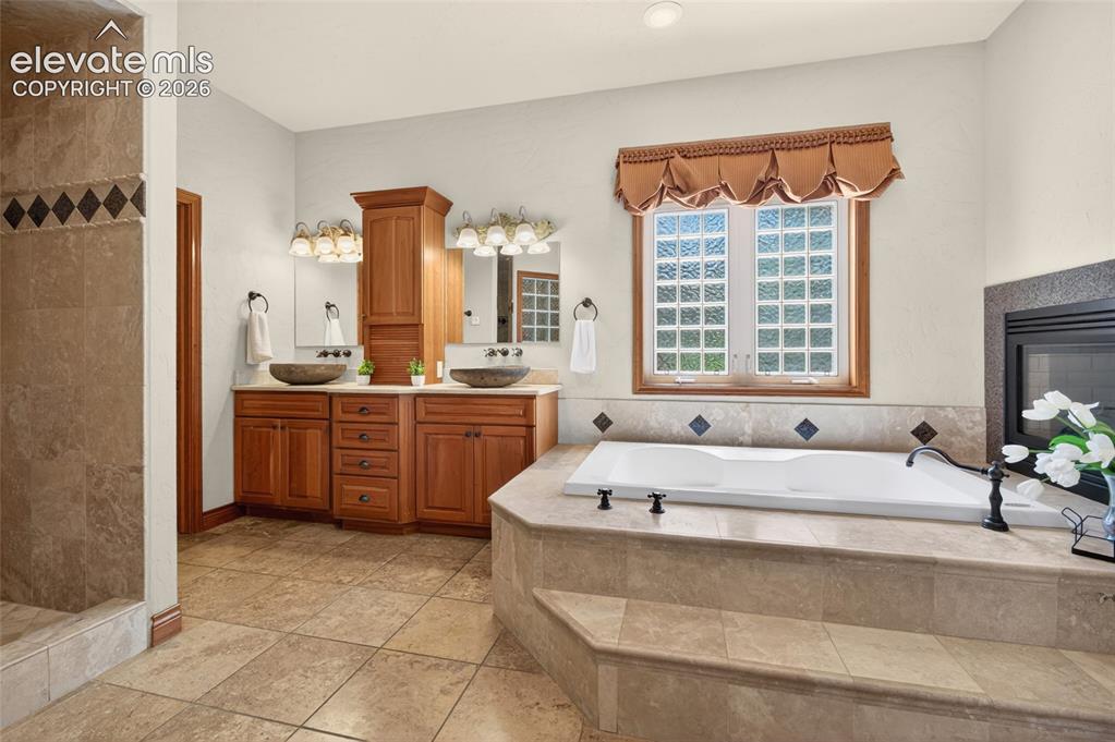Image 26 of 50: Spacious bathroom featuring a built-in soaking tub with surrounding tile, d