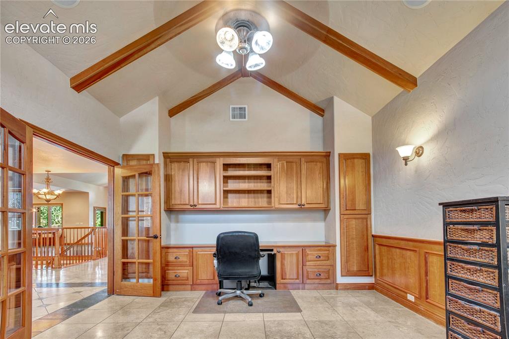Image 29 of 50: Vaulted ceilings with exposed wood beams, built-in cabinetry, wood-paneled