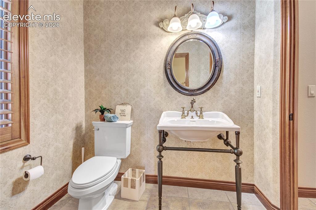 Image 30 of 50: Powder room featuring a pedestal sink with a bronze-finish base, an oval fr