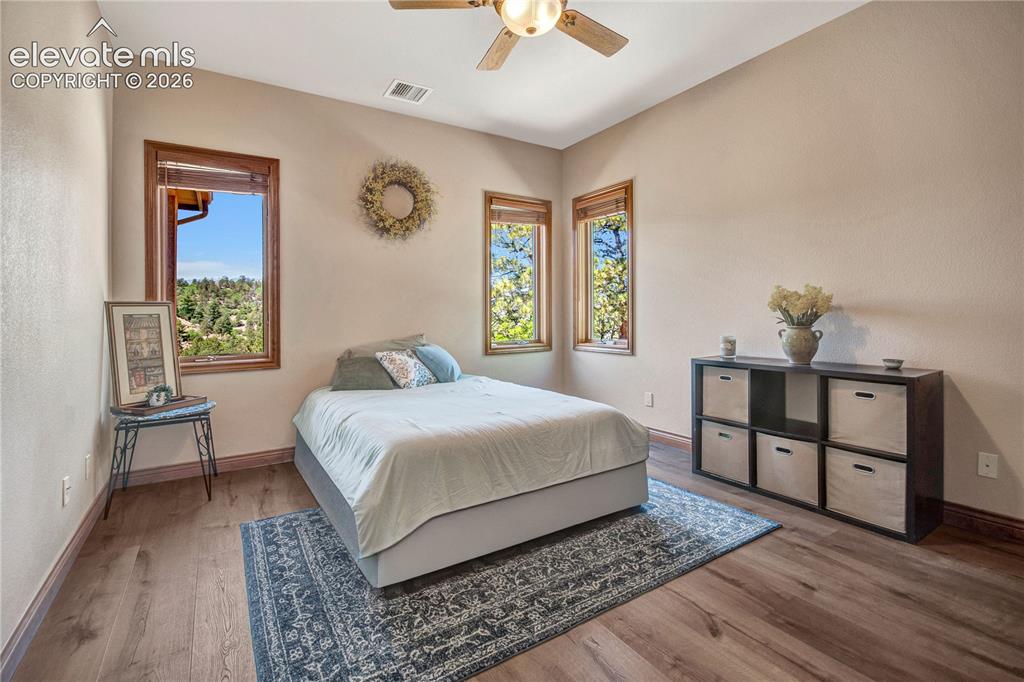 Image 31 of 50: Bedroom featuring wood-finish flooring, natural light through multiple wind