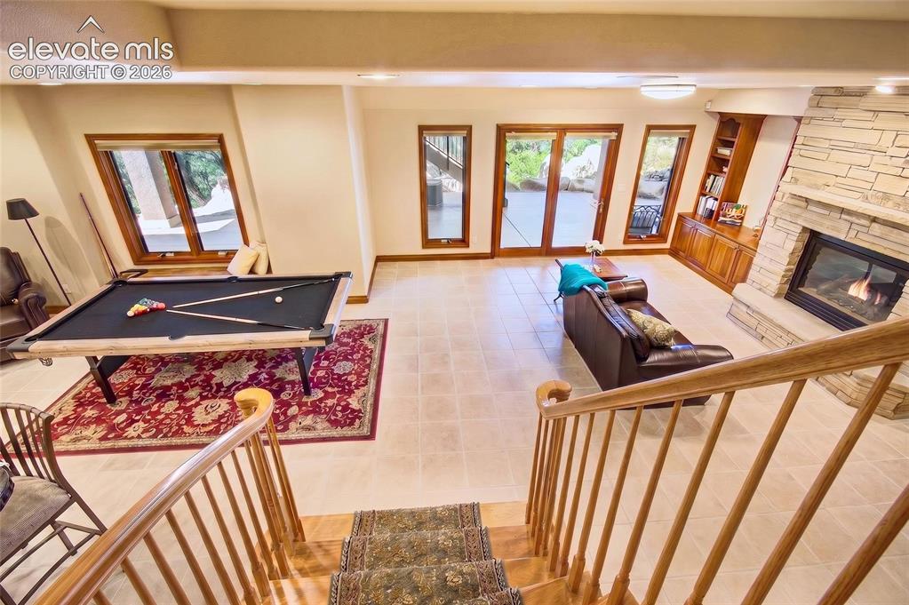 Image 36 of 50: Lower level entertainment space featuring tile flooring and a stacked stone