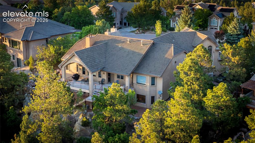 Image 4 of 50: Multi-level residence featuring a covered deck, stone accents, and a compos
