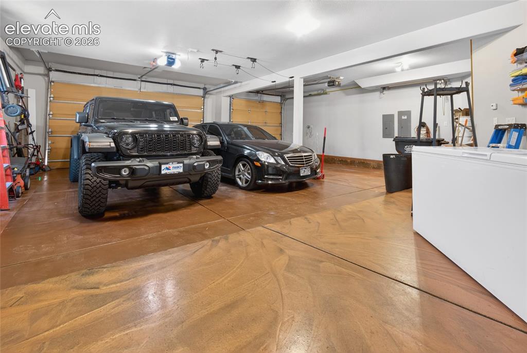 Image 46 of 50: Spacious garage featuring a finished floor, overhead lighting, and two gara